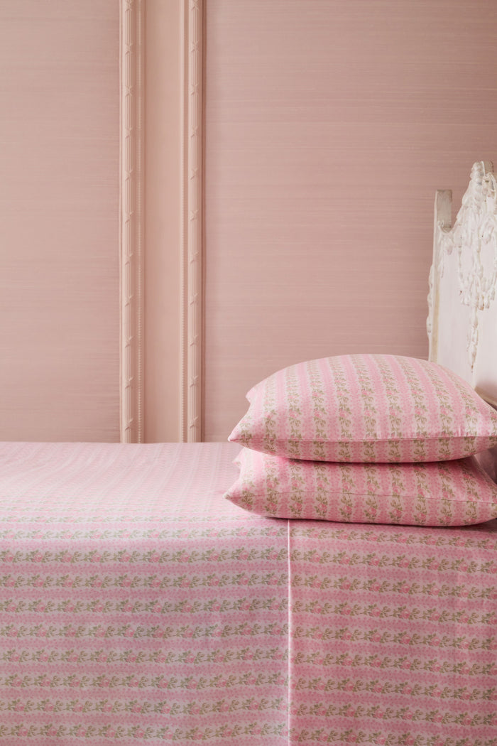 Pink printed sheet set on bed with matching pillowcases and floral striped pattern