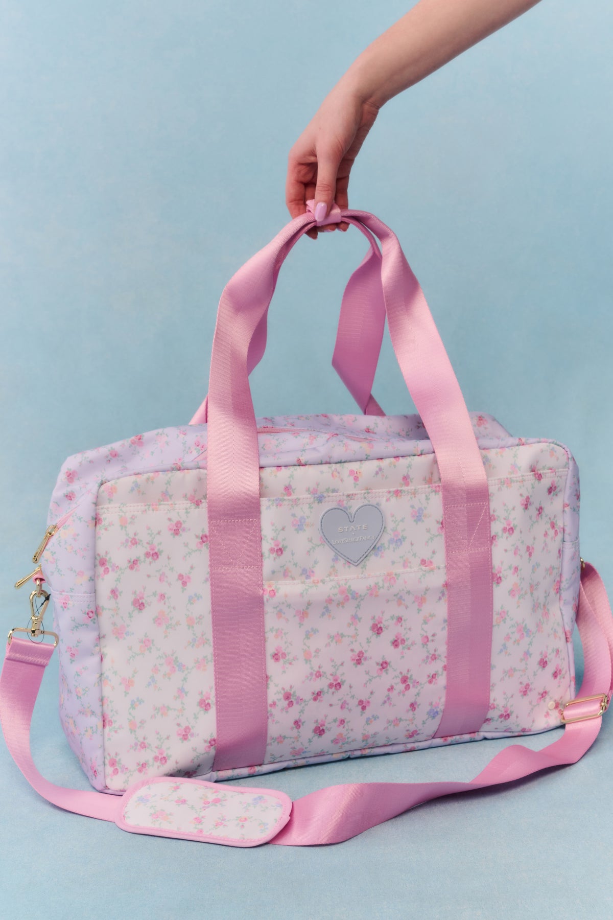 Floral duffel weekender bag with pink handles and heart logo patch, side zipper pocket