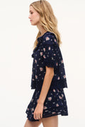 Navy floral cotton blouse with V-neck, ruffle sleeves, and tiered layered hem.