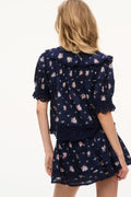 Navy floral cotton blouse back view with scalloped ruffle trim and tiered layers.