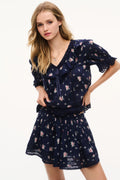 Navy floral cotton blouse with deep V-neck, short puff sleeves, and tiered skirt hem.