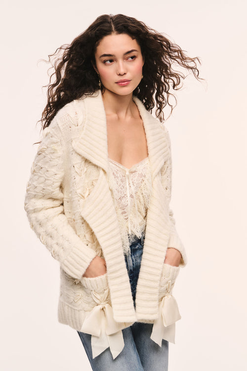 Windel ivory cardigan with textured cable knit, open front, shawl collar, ribbon threaded through the front and ribbon bows on the pockets