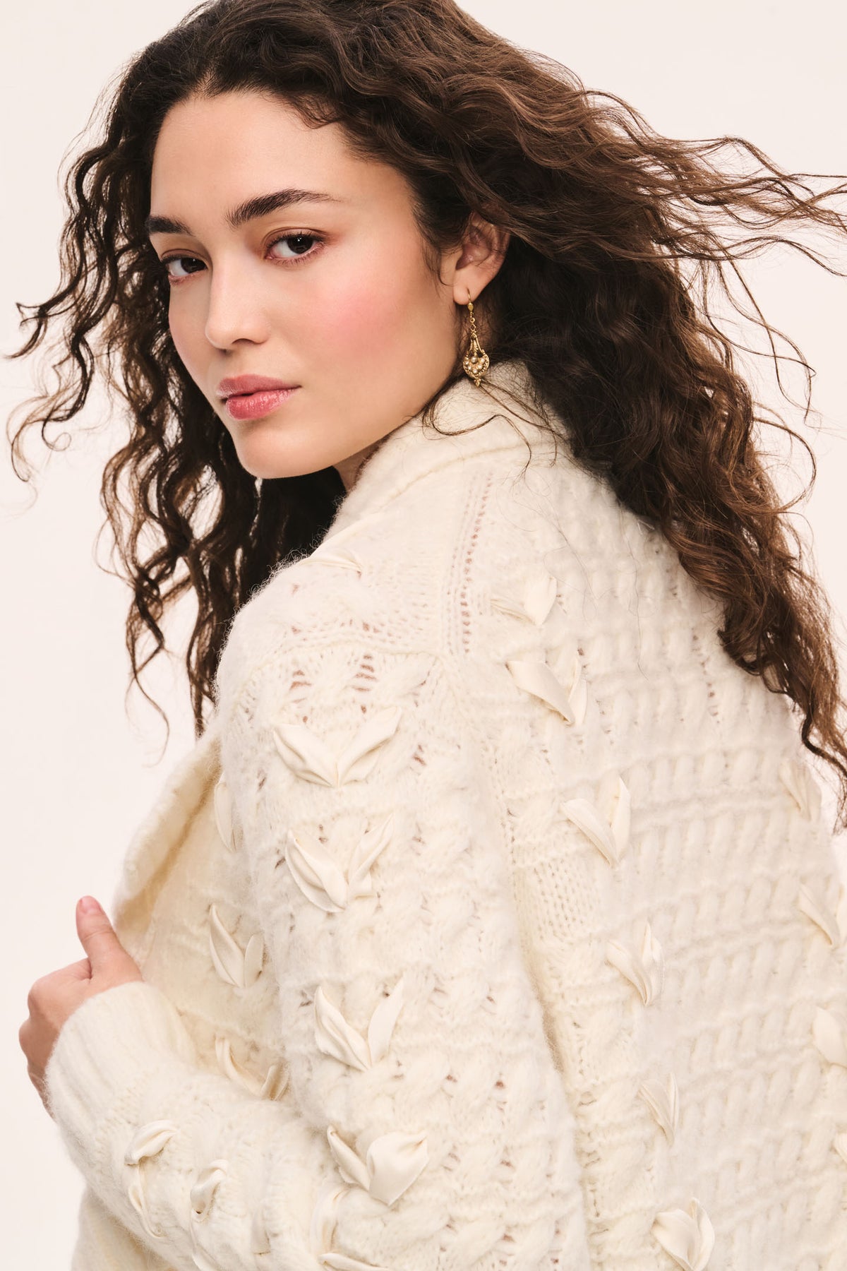 Windel ivory cardigan detail: ivory textured knit cardigan, open front with shawl collar, ribbon laced through the front, and ribbon bows on the pockets