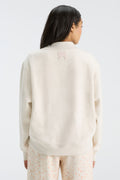 Rear view of cream mockneck crew sweatshirt with small logo detail near neckline