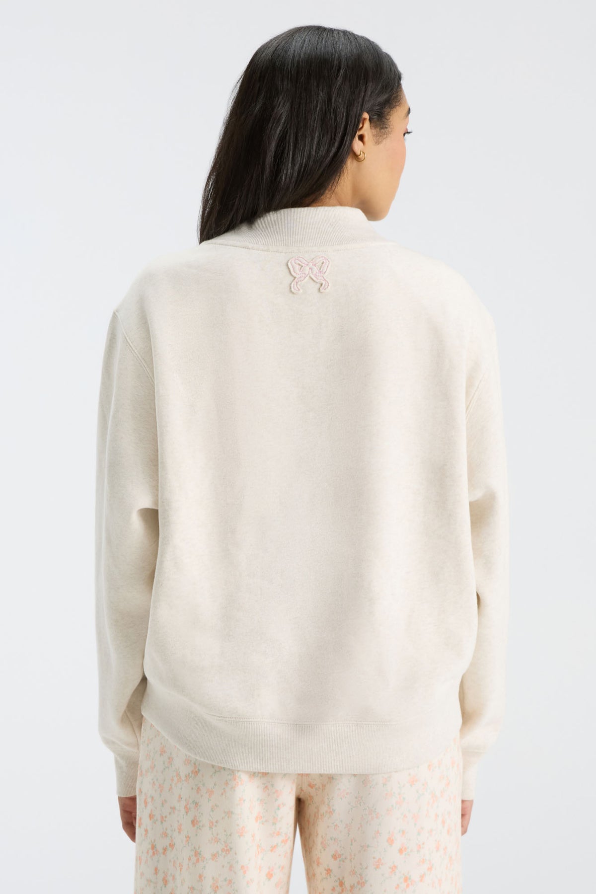 Rear view of cream mockneck crew sweatshirt with small logo detail near neckline