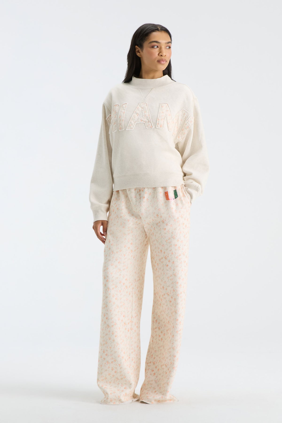 Cream floral-print sweatpants with elastic waistband, drawstring, and wide legs