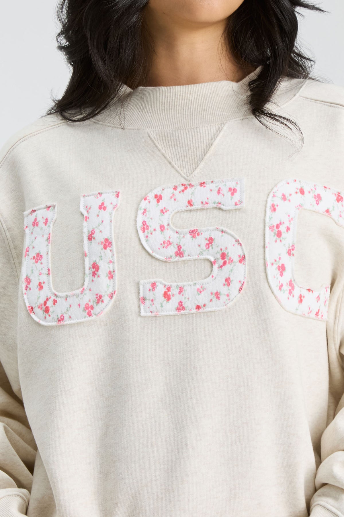 Cream mockneck crew sweatshirt close-up of pink floral “U S C” letter print