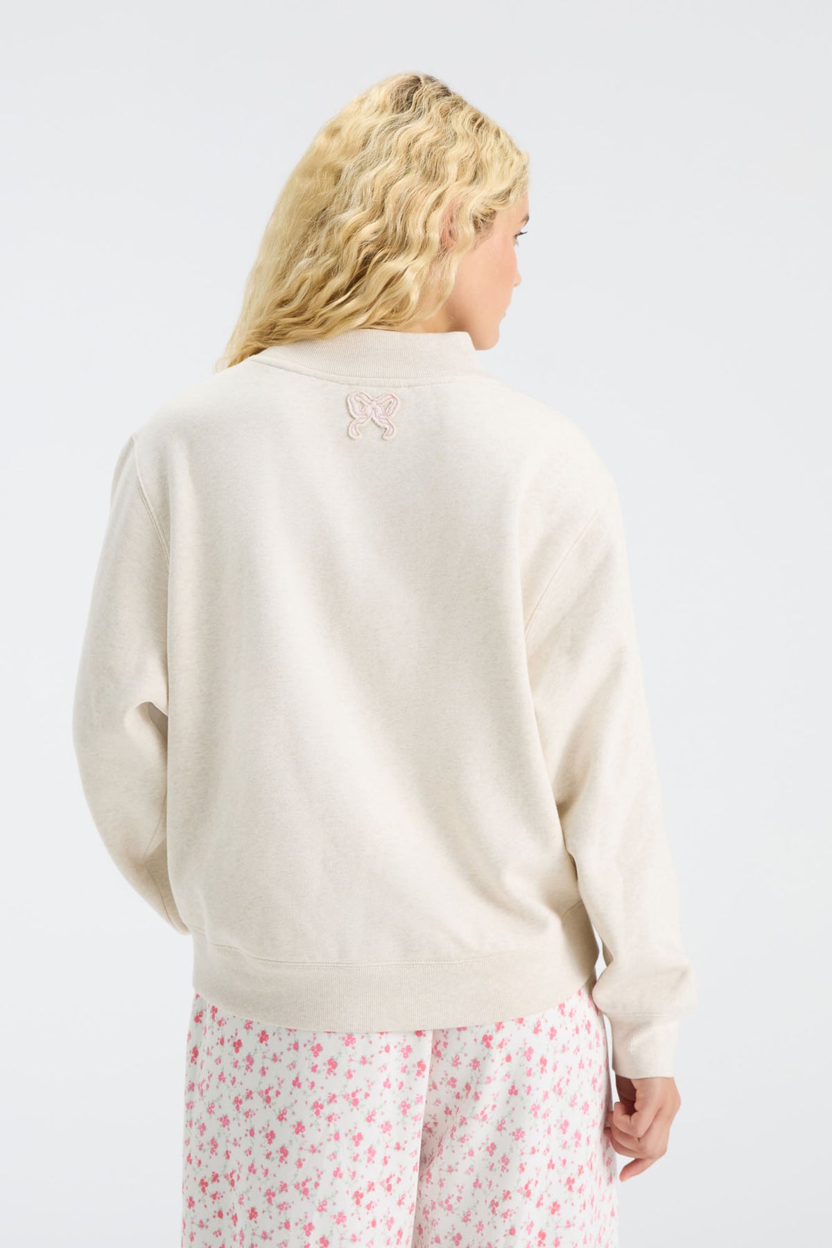 Cream mockneck crew sweatshirt with small back logo and pink floral pajama-style pants