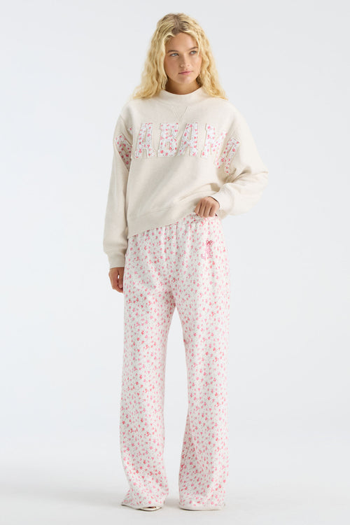 Cream sweatpants with pink floral print, elastic waist, and wide flared legs