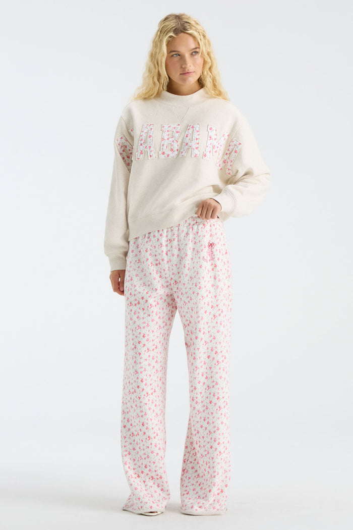 Cream sweatpants with pink floral print, elastic waist, and wide flared legs