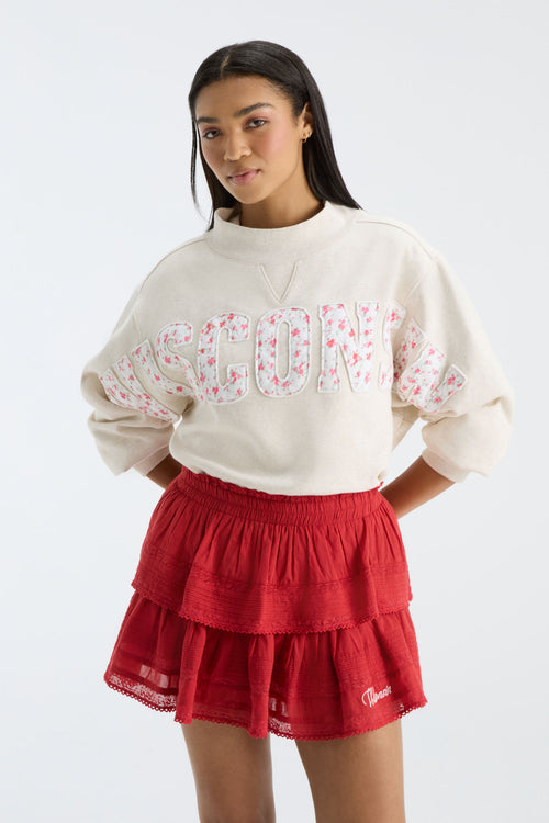 Cream mockneck pullover with long sleeves and large “FANATICS” letters in pink floral