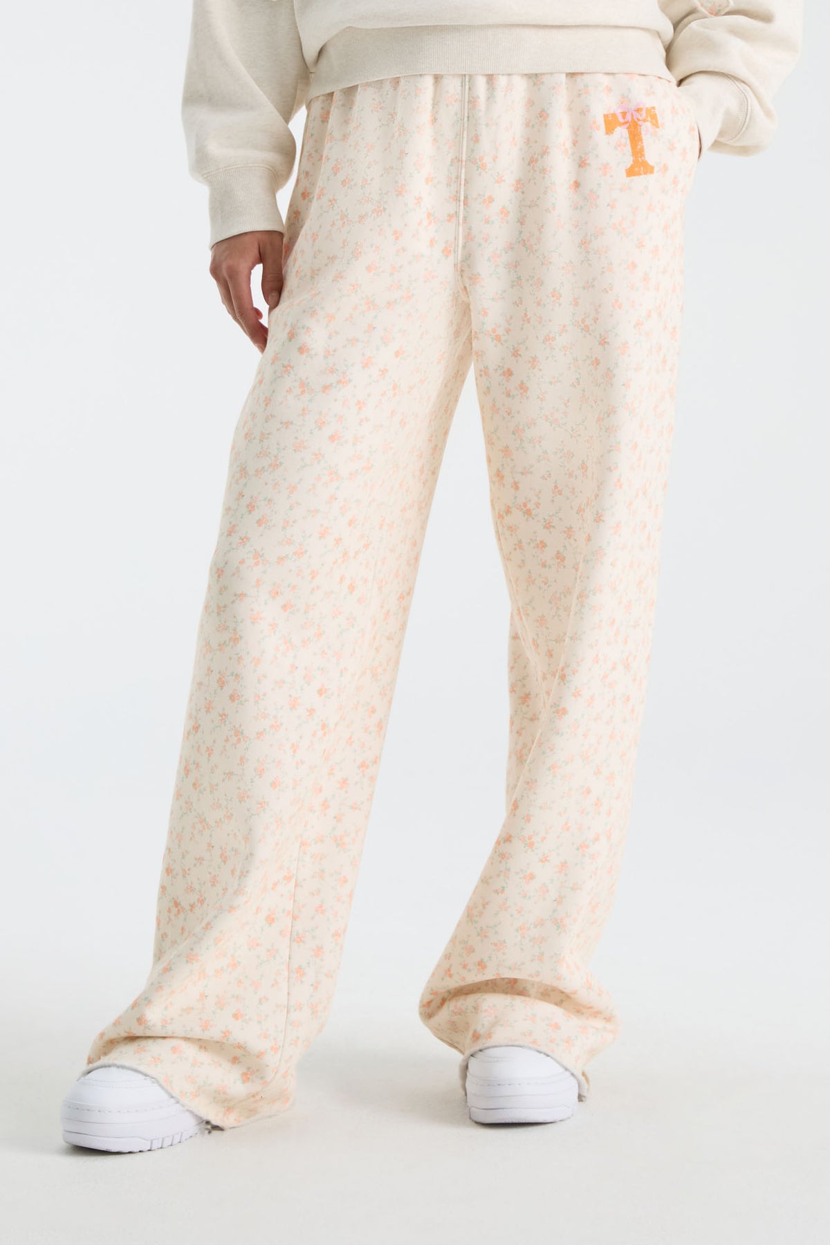 Cream floral sweatpants with elastic cuffs and wide flared legs