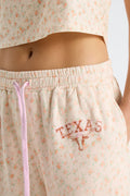 Close-up of elastic waistband and pink drawstring on women’s floral sweatpants with Texas logo