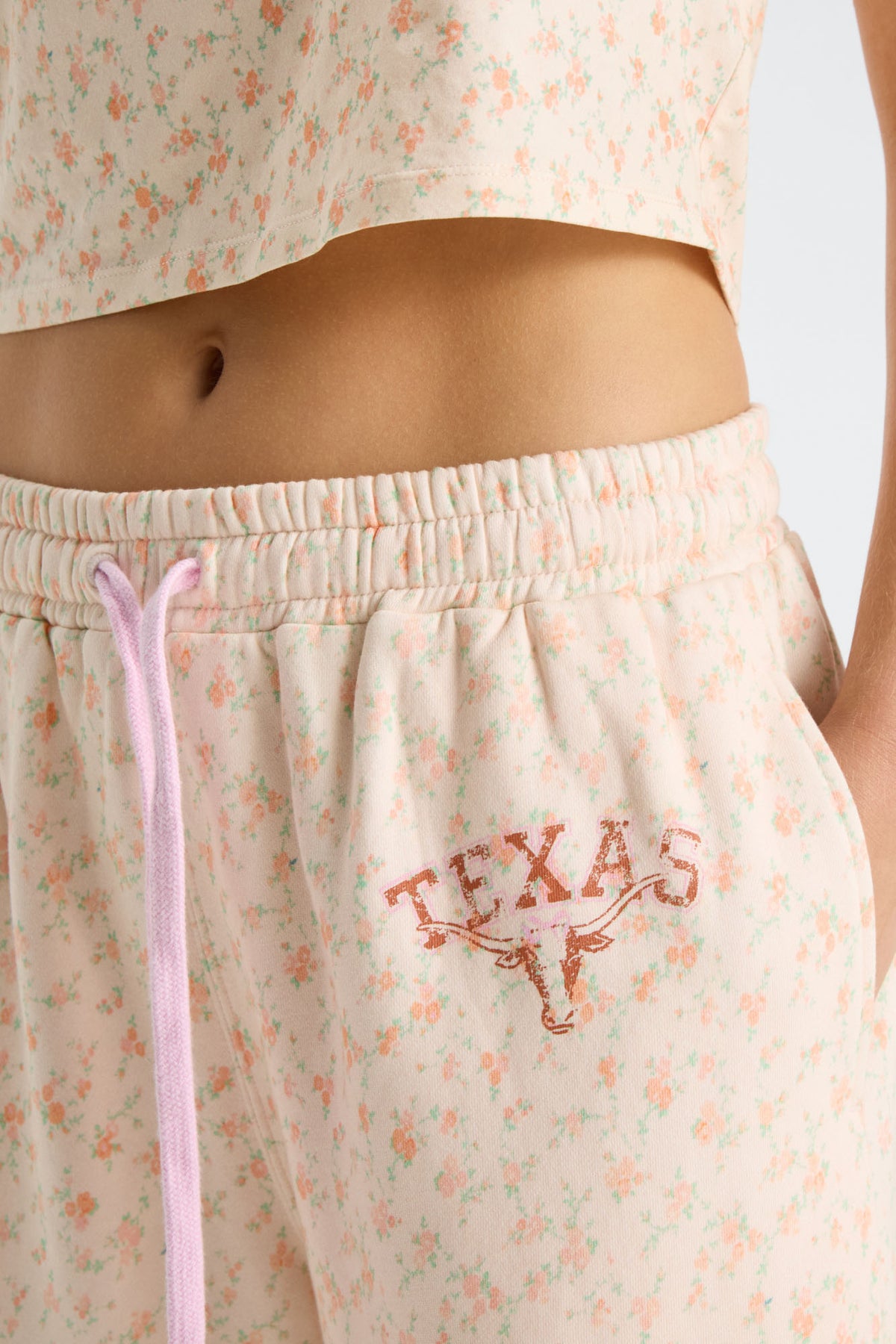 Close-up of elastic waistband and pink drawstring on women’s floral sweatpants with Texas logo
