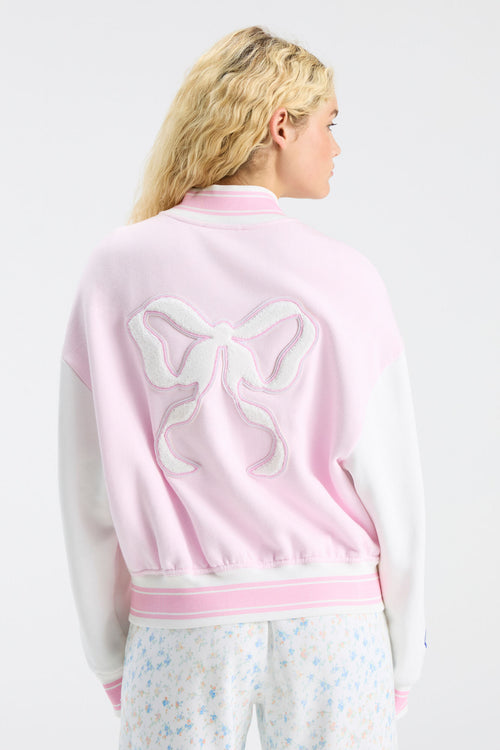 Back view of light pink varsity jacket with large bow-shaped embroidered emblem