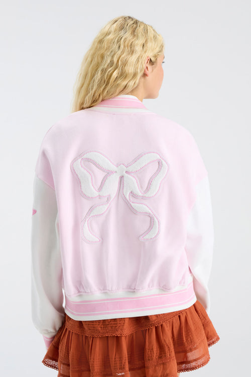 Pink varsity jacket with white sleeves, striped trim, and large bow embroidery on back