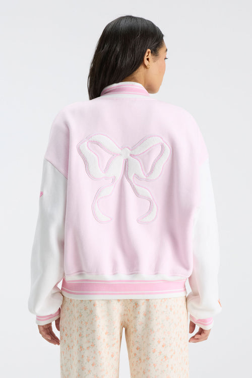 Pink varsity jacket with white sleeves and large bow graphic on the back.