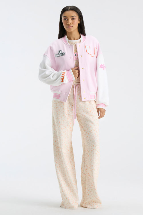 Pink collegiate varsity jacket with button front, striped cuffs, and letterman patches
