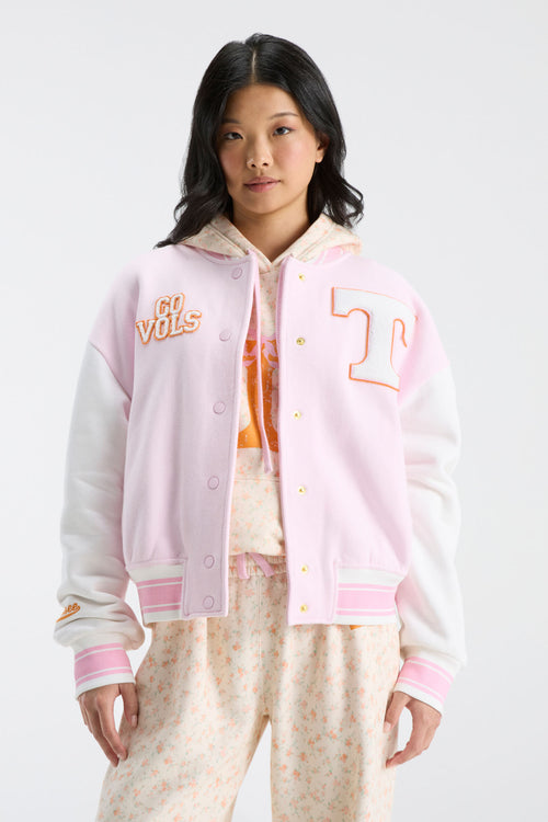 Pink varsity jacket with snap front, ribbed cuffs, and orange logo applique on right chest