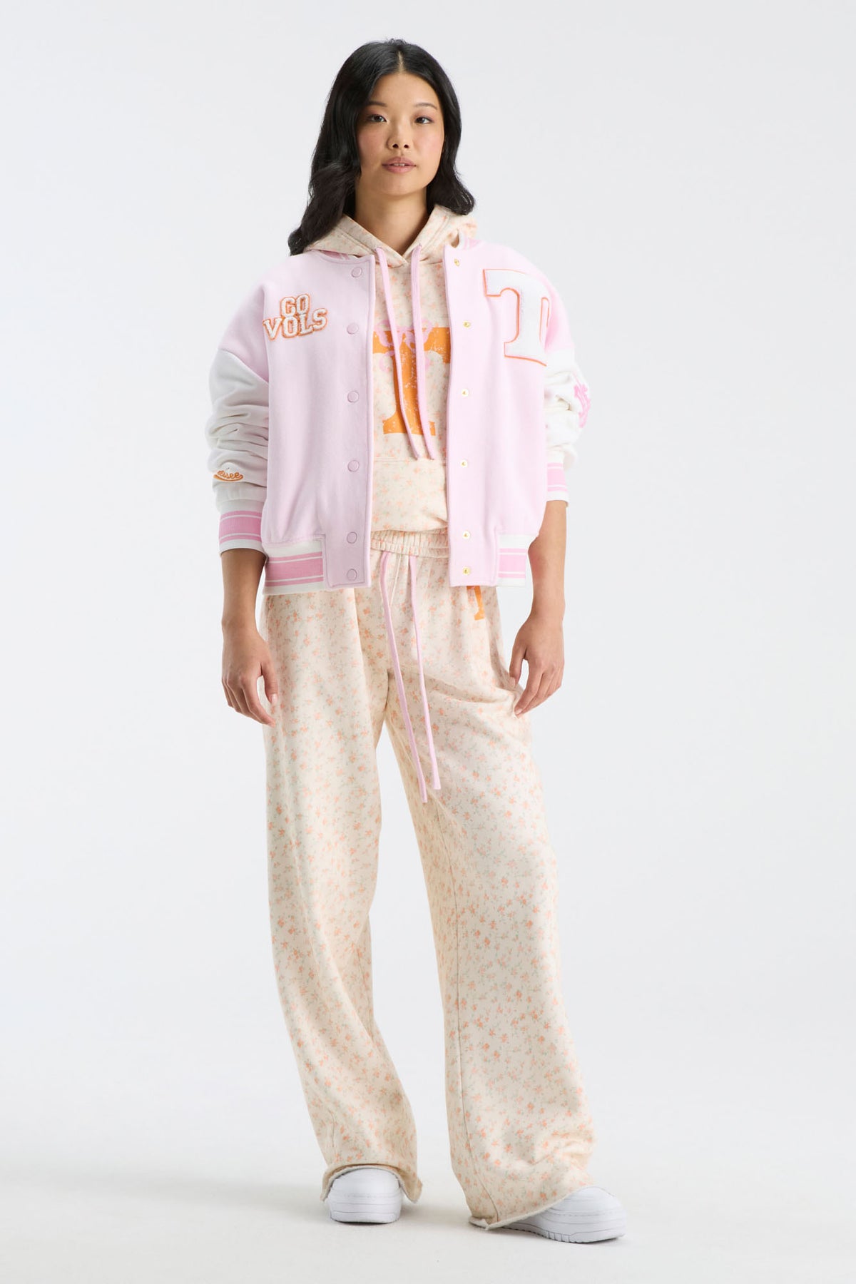 Pink varsity jacket worn over floral top, featuring snap front and striped rib trim