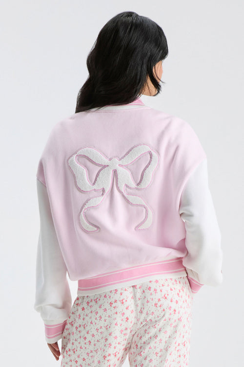 Light pink varsity jacket back with bow applique and ribbed striped waistband trim.