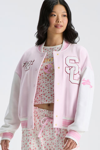 Light pink varsity jacket with snap buttons, contrast trim, and embroidered team-style graphics