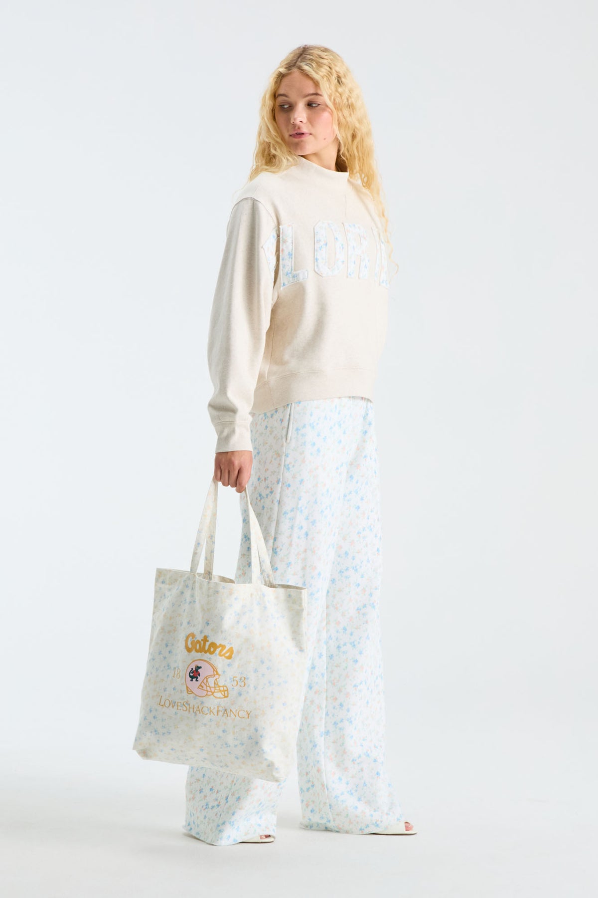 Cream mockneck crew sweatshirt with “LOVE” applique; worn with blue patterned pants