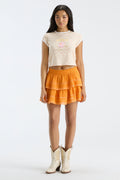 Cropped light-pink floral ringer tee with crew neck; model wears orange tiered skirt