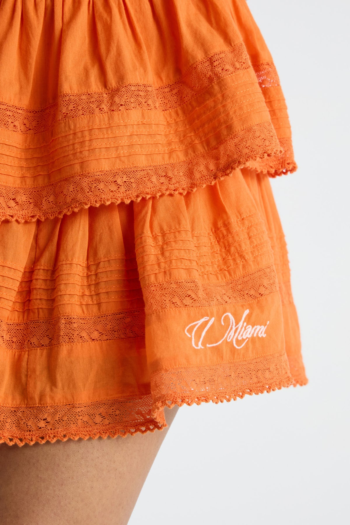 Bright orange tiered ruffle mini skirt with lace hem and “Miami” embroidery