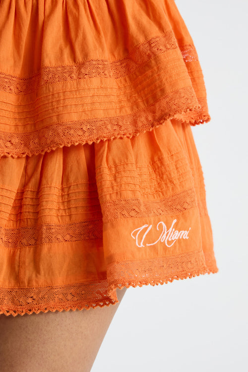 Bright orange tiered ruffle mini skirt with lace hem and “Miami” embroidery