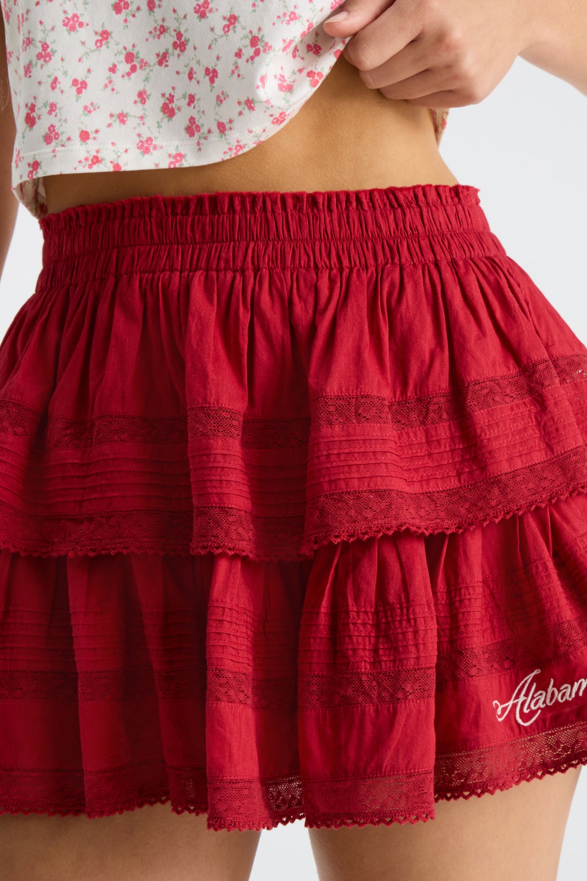Crimson ruffle mini skirt with textured tiers and lace trim at hem.