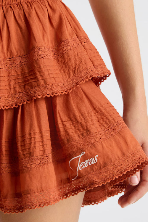 Burnt orange mini skirt with textured tiers and lace-edged hem detail.