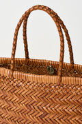 Mini woven tote bag close-up with braided handles and circular emblem at front