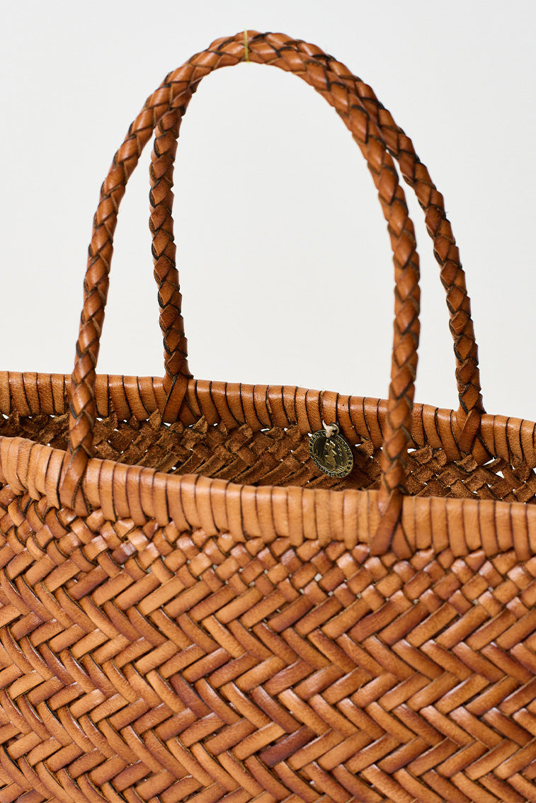 Mini woven tote bag close-up with braided handles and circular emblem at front