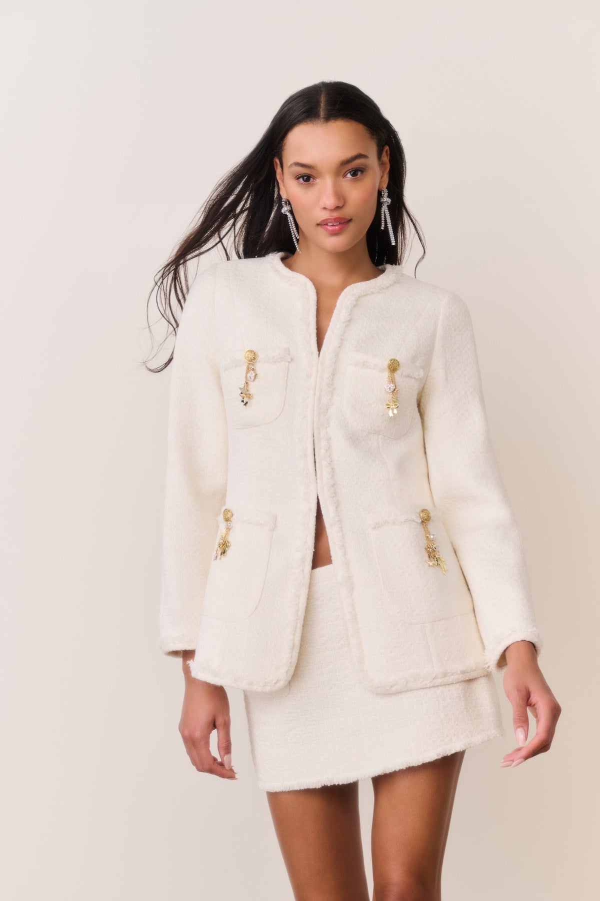 Cream tweed jacket with gold-tone charm trim, stand collar, and flap patch pockets