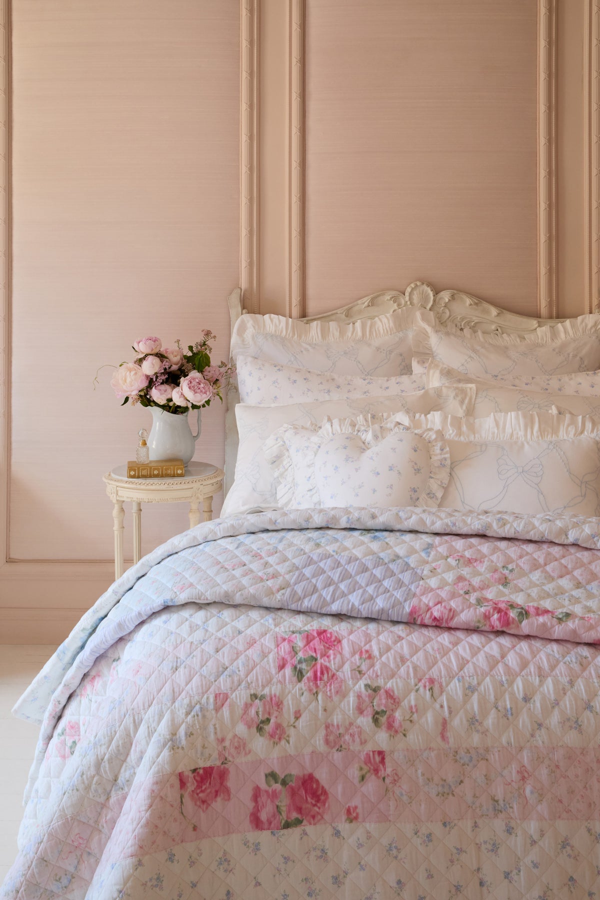 Light quilt with diamond quilting and pink floral patchwork, folded on bed
