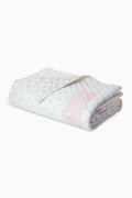 Light patchwork quilt with pale blue and pink floral blocks, rolled view