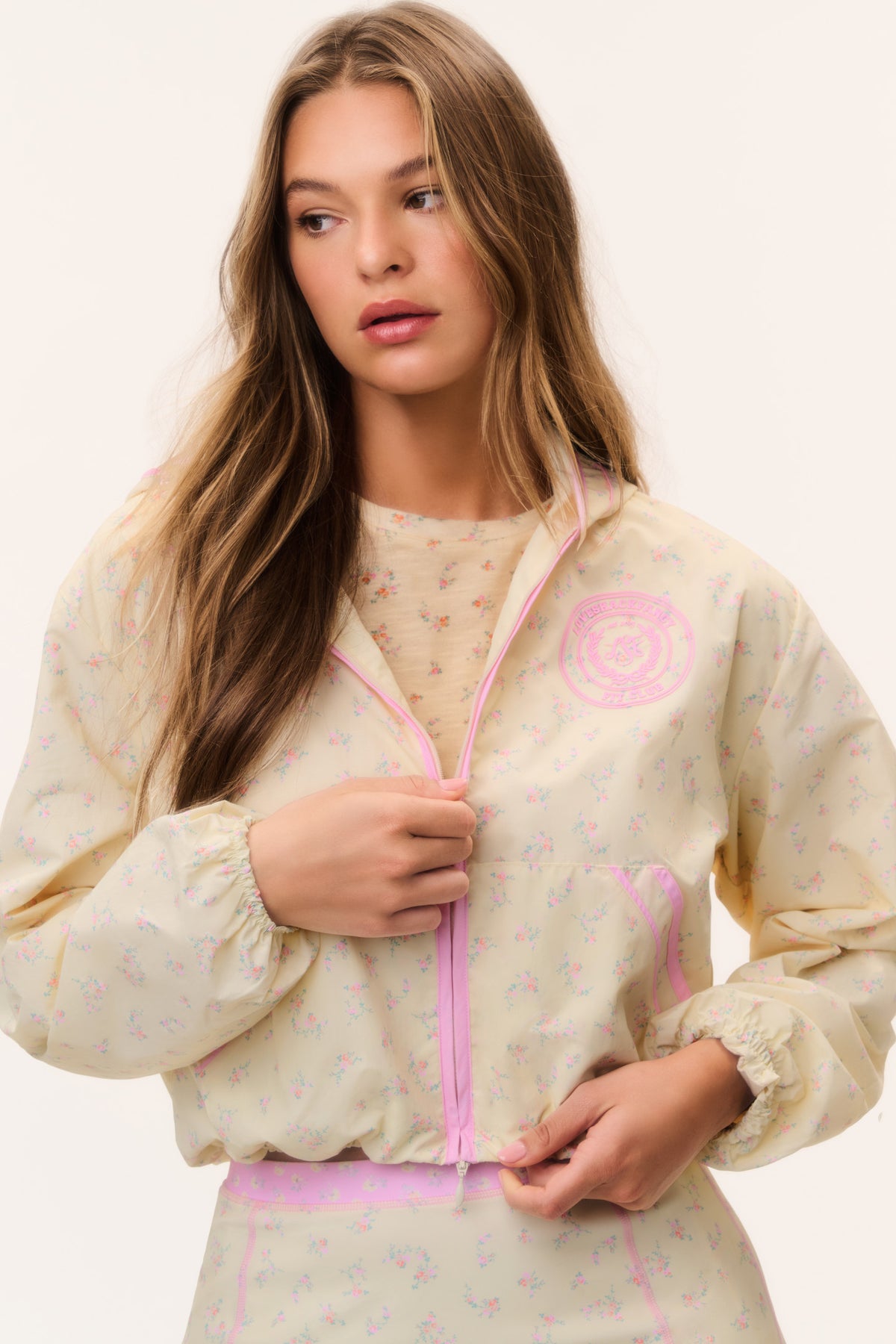 Cream windbreaker hoodie with pink zipper, hood, and all-over pastel print