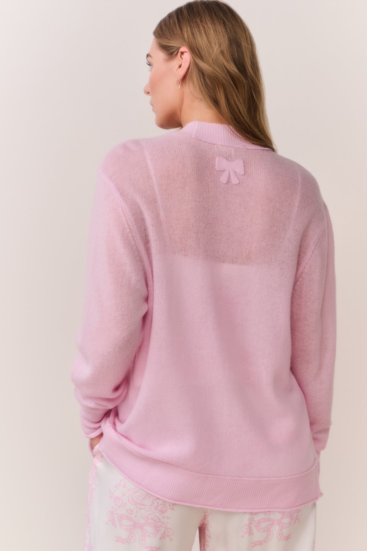 Back view of pink cashmere cardigan with small bow detail at upper back