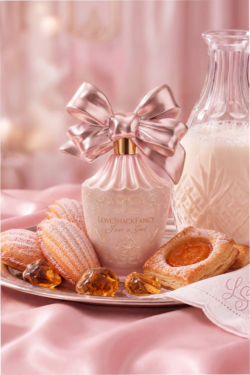 Pink perfume bottle with bow on a tray with amber-colored candies