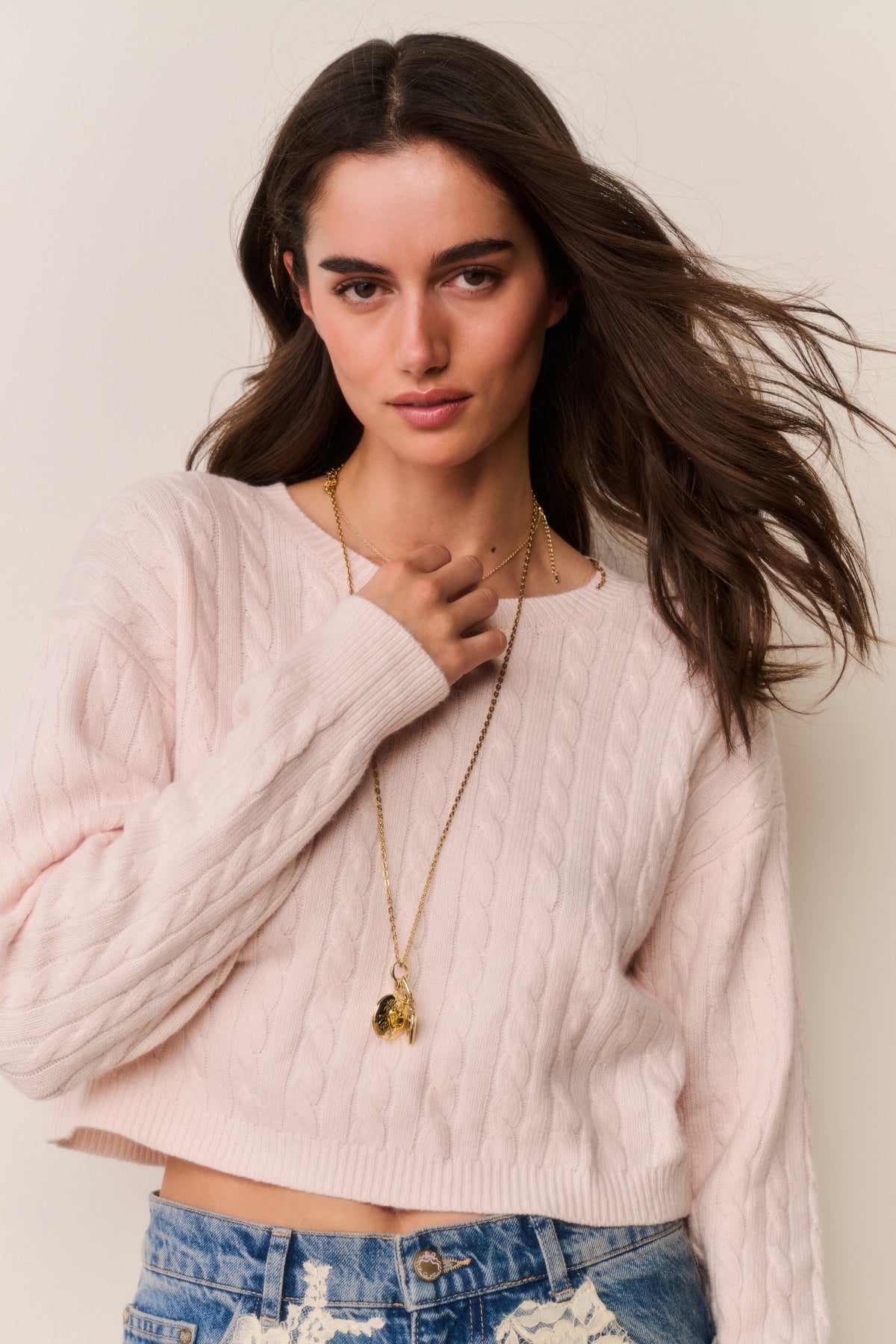 Cropped pale pink cable knit sweater with ribbed crew neck and long sleeves