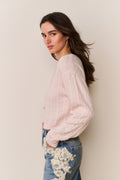 Cropped pale pink cable knit pullover sweater shown from the side