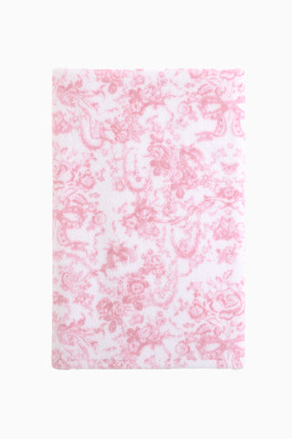 Cotton bath towel, pink with repeating floral bow pattern, plush terry surface.