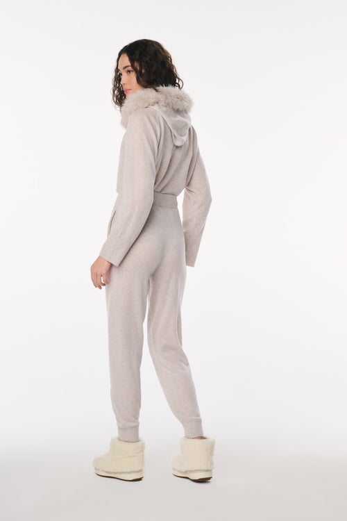 Person wearing a gray jumpsuit with a hood on a white background