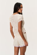 Floral short-sleeve blouse back view with lace-trim scalloped hem and puff sleeves