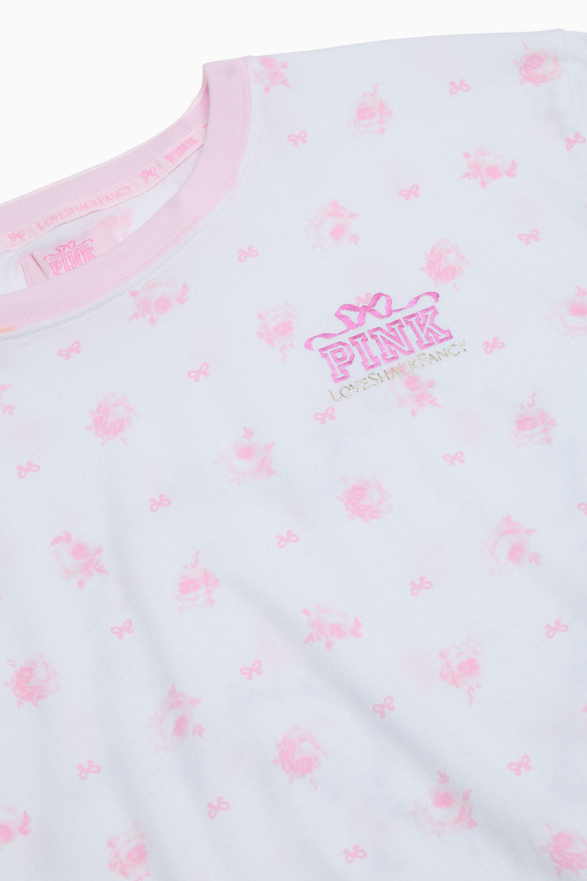 Close-up of light pink cotton tee with small bow pattern and “PINK” emblem
