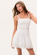 White cotton mini dress front view with thin straps, button-front design, tiered ruffles, lace