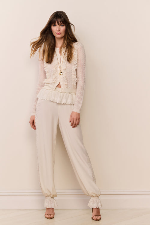 Cream lace-trimmed balloon pants with relaxed fit and elastic ruffle cuffs