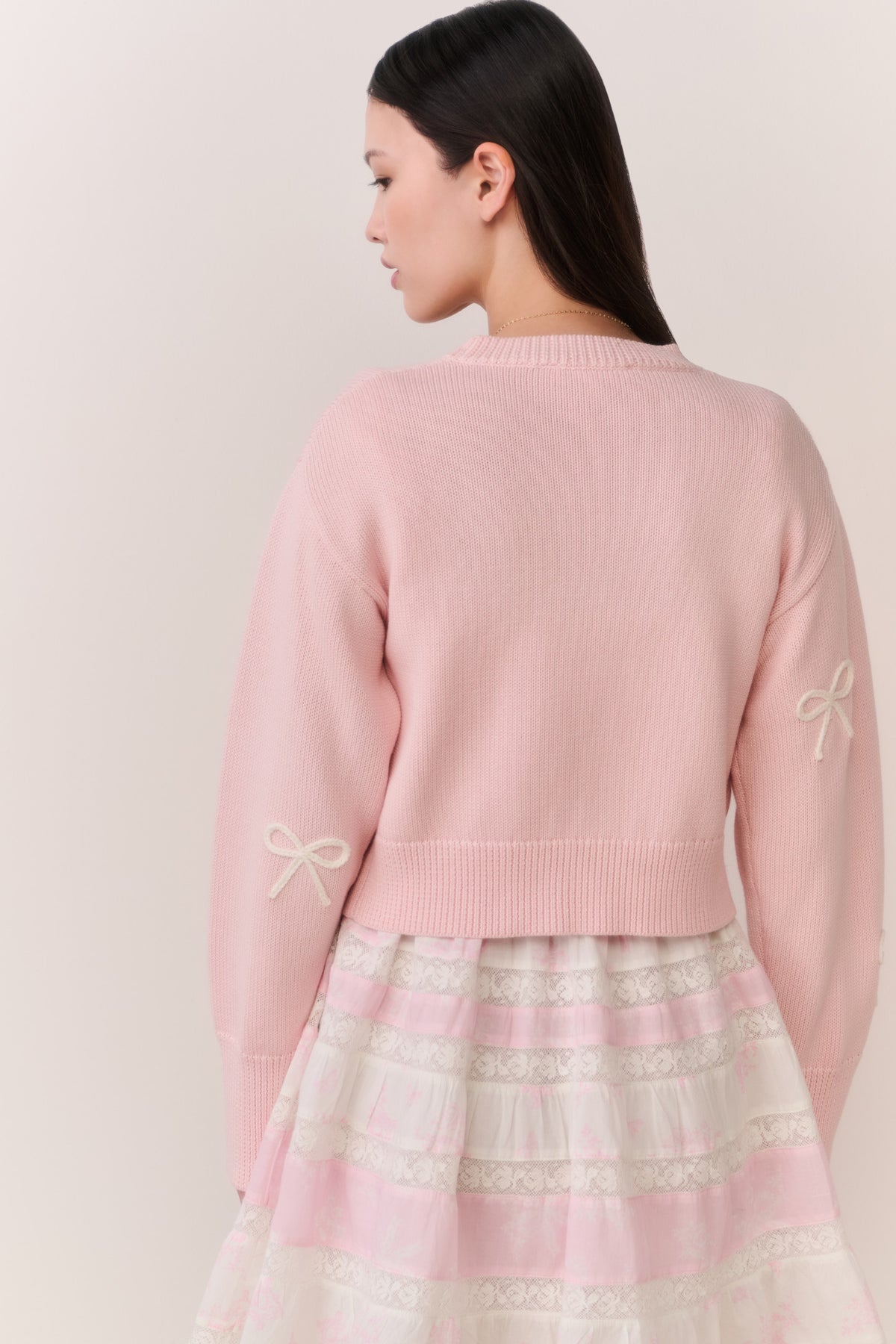 Petal pink cardigan back view with bow embroidery on the right sleeve