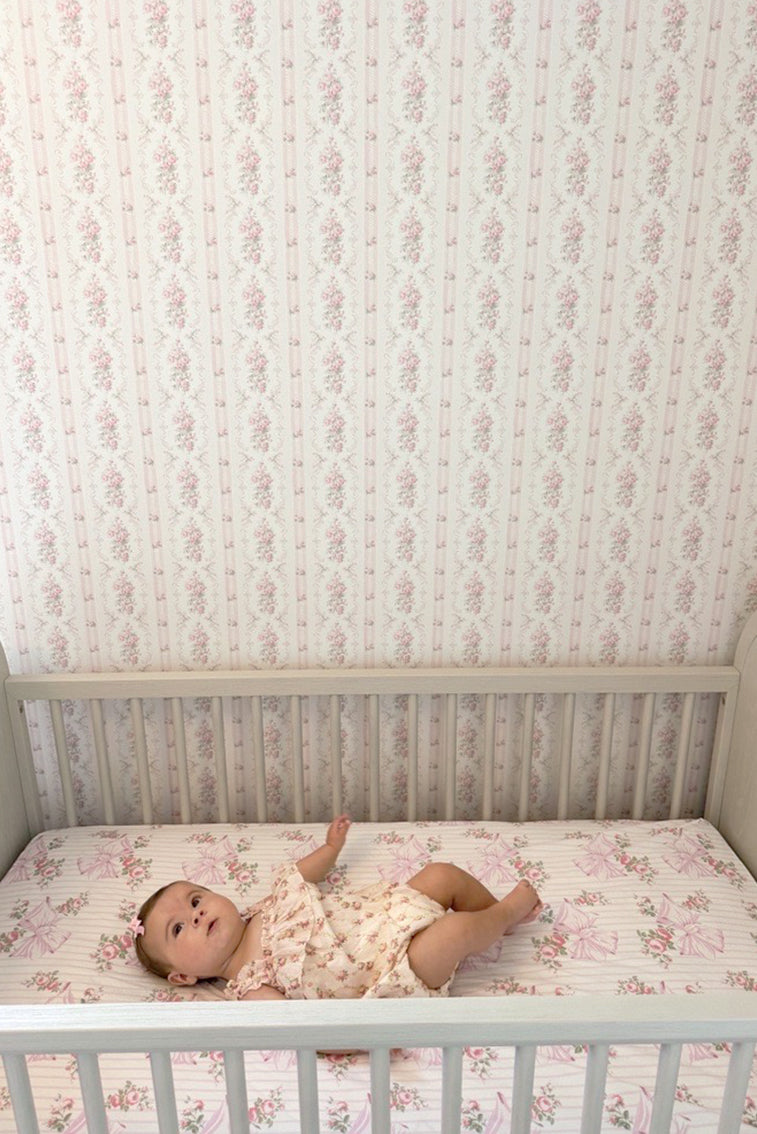 Cotton crib sheet in striped pink floral print, fitted on crib mattress